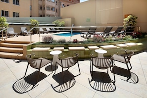 Zona de piscina en la azotea con sillones reclinables y una pequeña mesa.