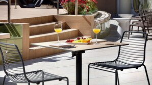 Un patio al aire libre con una mesa, sillas, una bandeja de fruta y dos vasos de jugo de naranja.