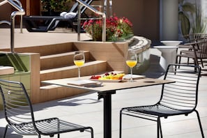 An outdoor patio with a table and chairs, a fruit plate, and two glasses of orange juice.