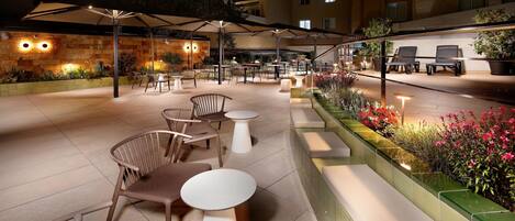 An outdoor patio area with seating, tables, and umbrellas.
