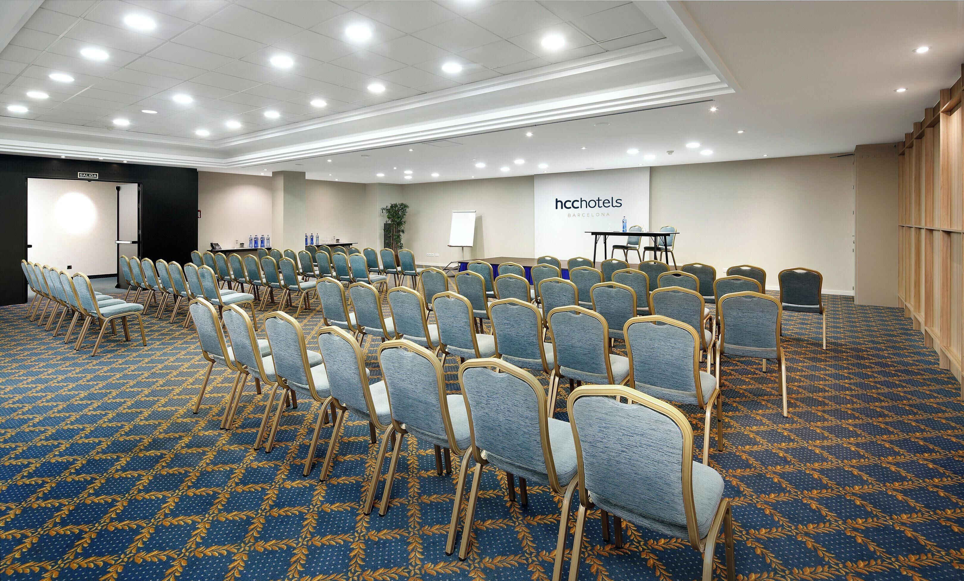 A conference room with rows of chairs, a whiteboard, and a table with water bottles.