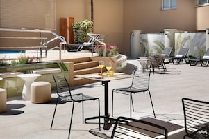 An outdoor patio with lounge chairs, a small table with drinks, and a pool area.