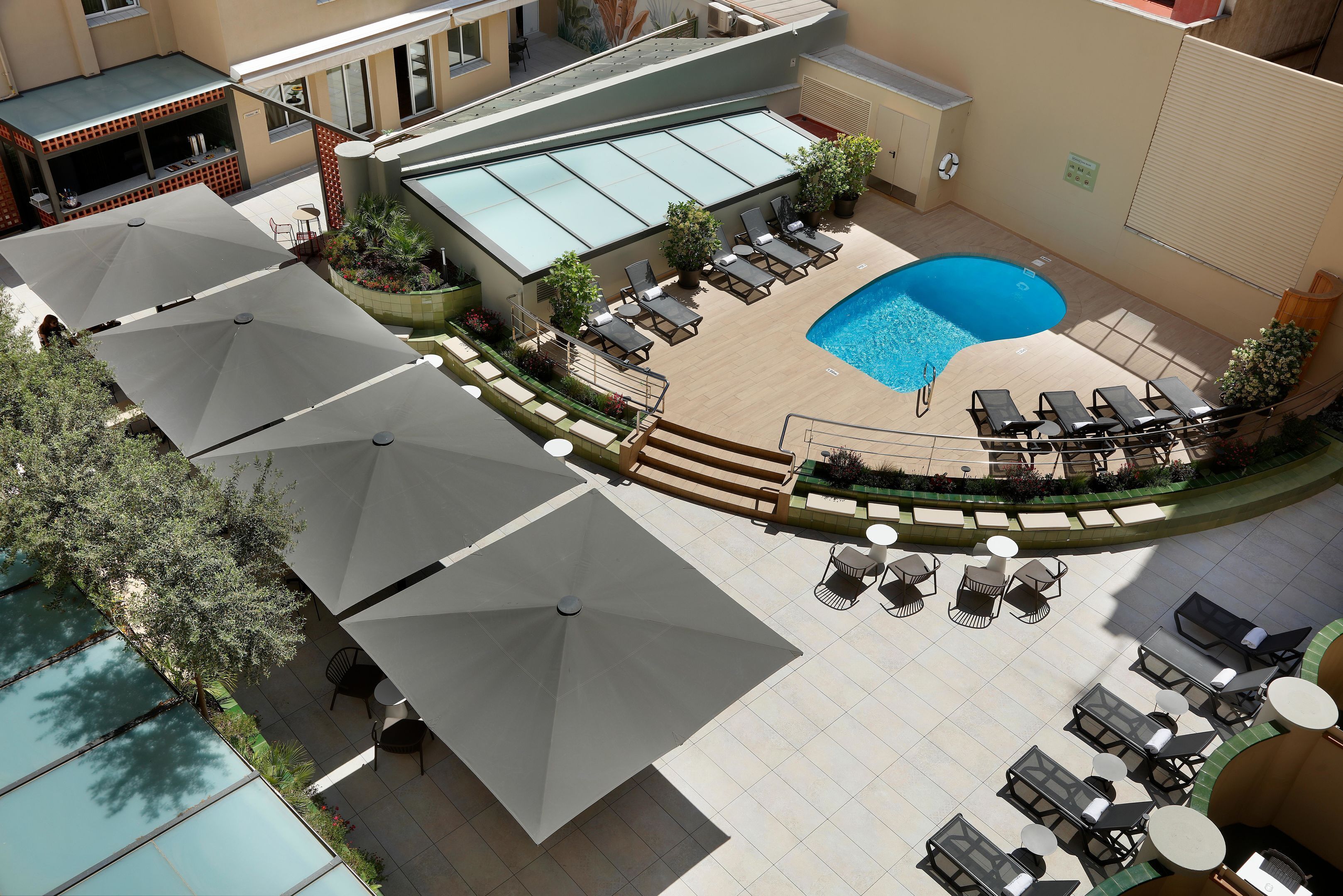 A rooftop pool area with sun umbrellas, lounge chairs, and a small pool.