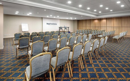 A conference room with rows of chairs, a whiteboard, and a wooden panel wall.