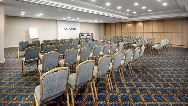 Un salón de conferencias con filas de sillas, una pizarra y un panel de pared de madera.