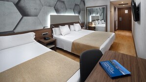 Habitación de hotel con dos camas, un escritorio de madera, un libro titulado 'Hotel Services Directory' y un espejo en la pared.