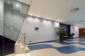 Un vestíbulo moderno con una escalera de cristal, un suelo estampado y una estatua de león.