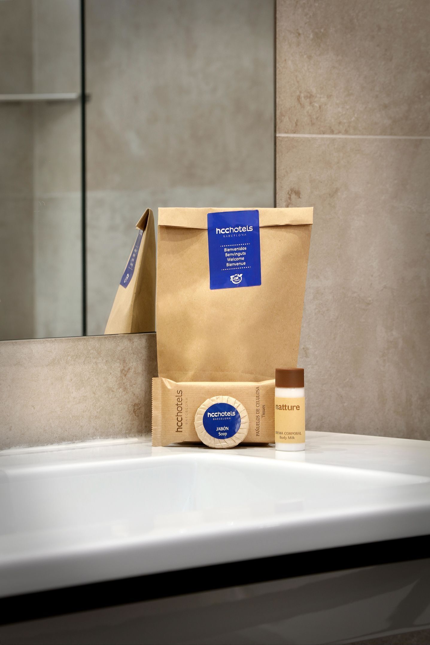 A bathroom counter with toiletries including a brown paper bag, a soap bar, and a bottle of body milk.
