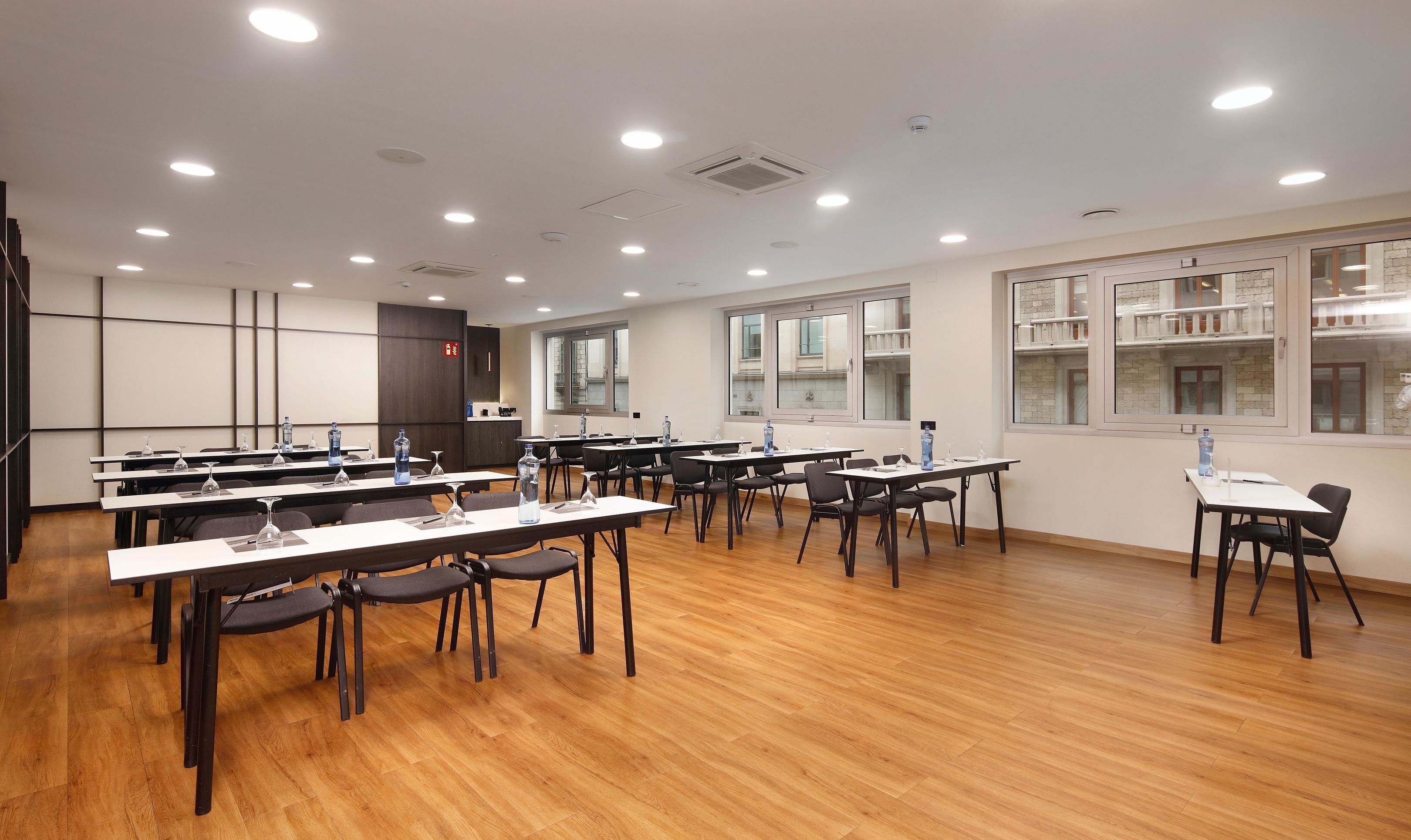 Une salle de conférence équipée de plusieurs tables, de chaises et de bouteilles d’eau.
