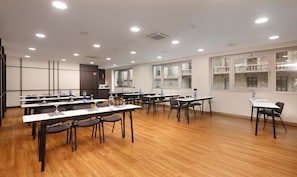 Un salón de conferencias con varias mesas, sillas y botellas de agua.