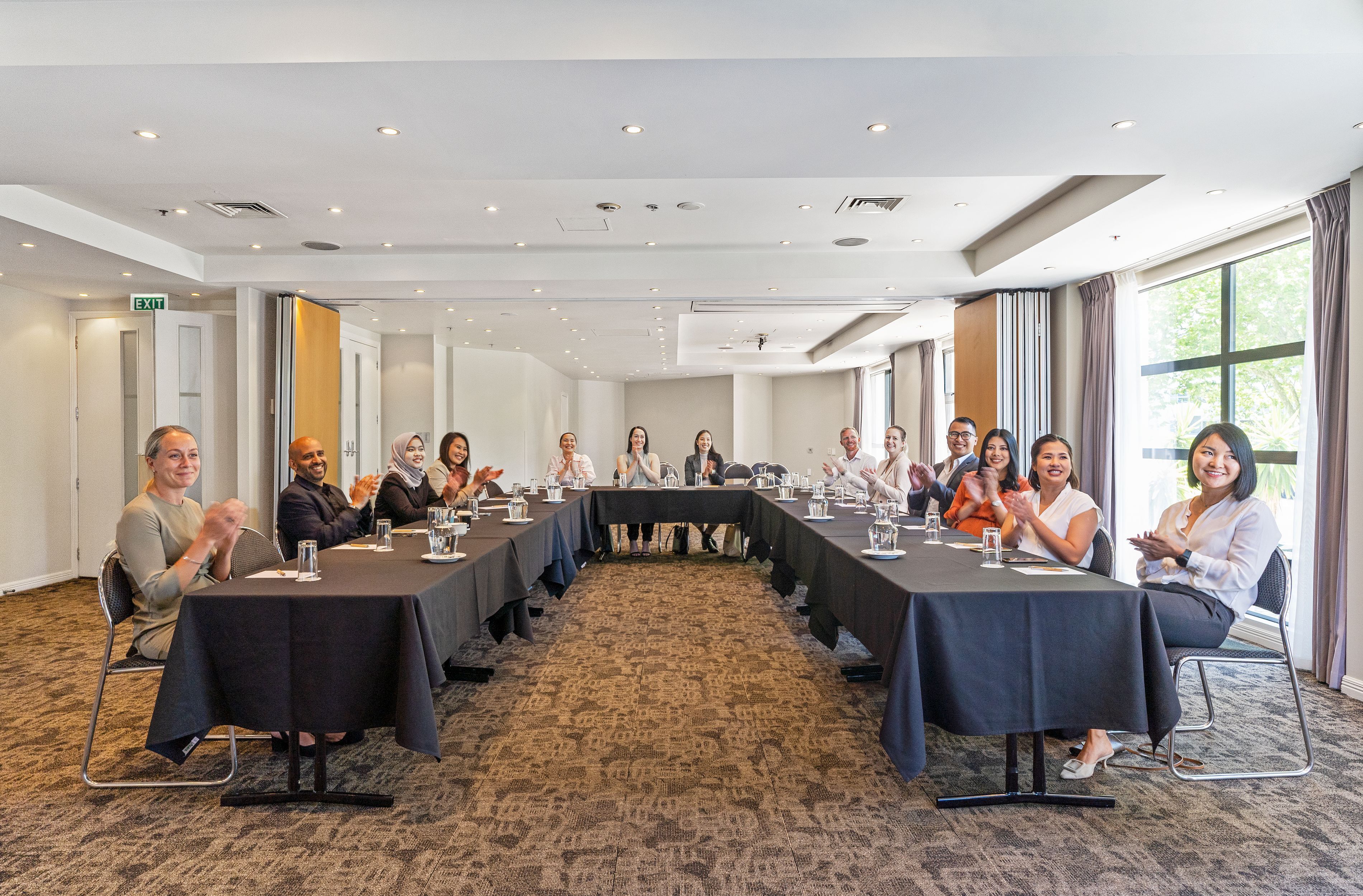 A conference room with a long table, chairs, and a carpeted floor.