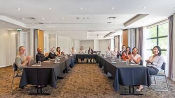 A conference room with a long table, chairs, and a carpeted floor.