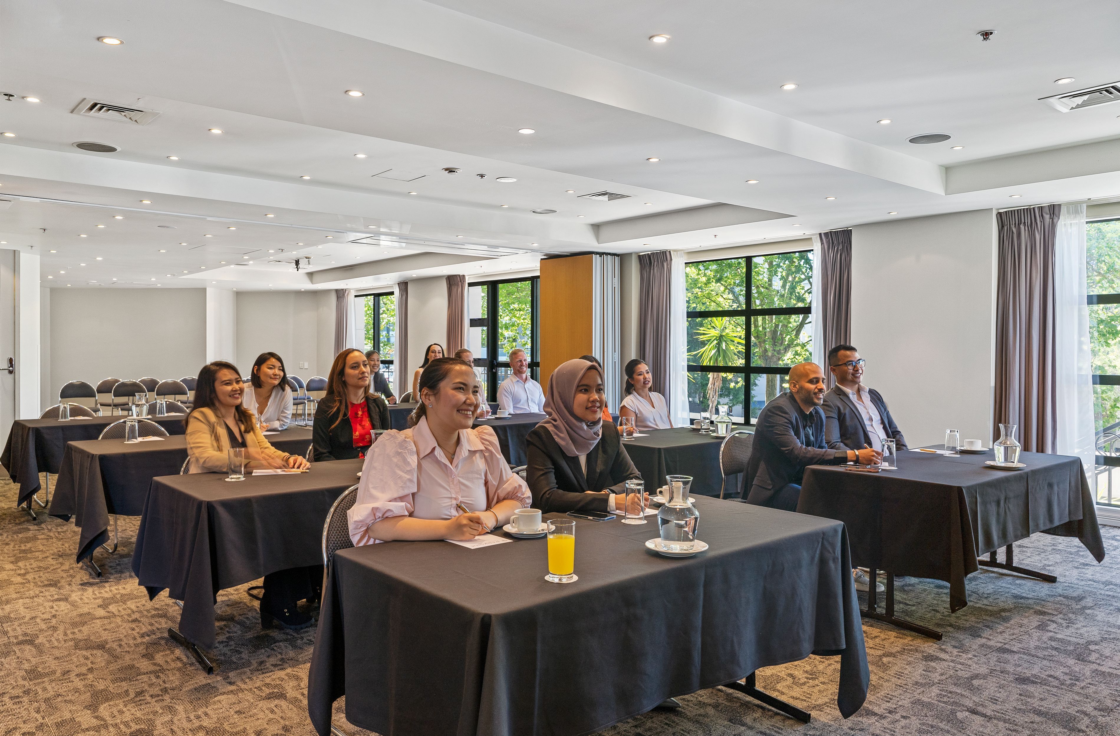 Une salle de conférence équipée de tables, de chaises et accueillant des participants.