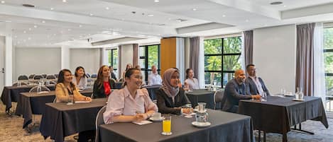 Une salle de conférence équipée de tables, de chaises et accueillant des participants.