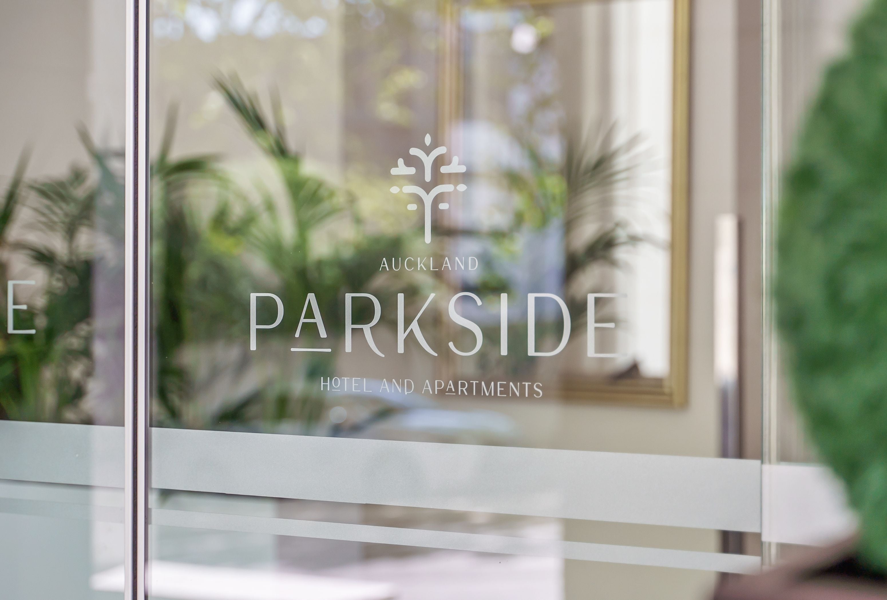 Een glazen raam met de tekst 'AUCKLAND PARKSIDE HOTEL AND APARTMENTS'.
