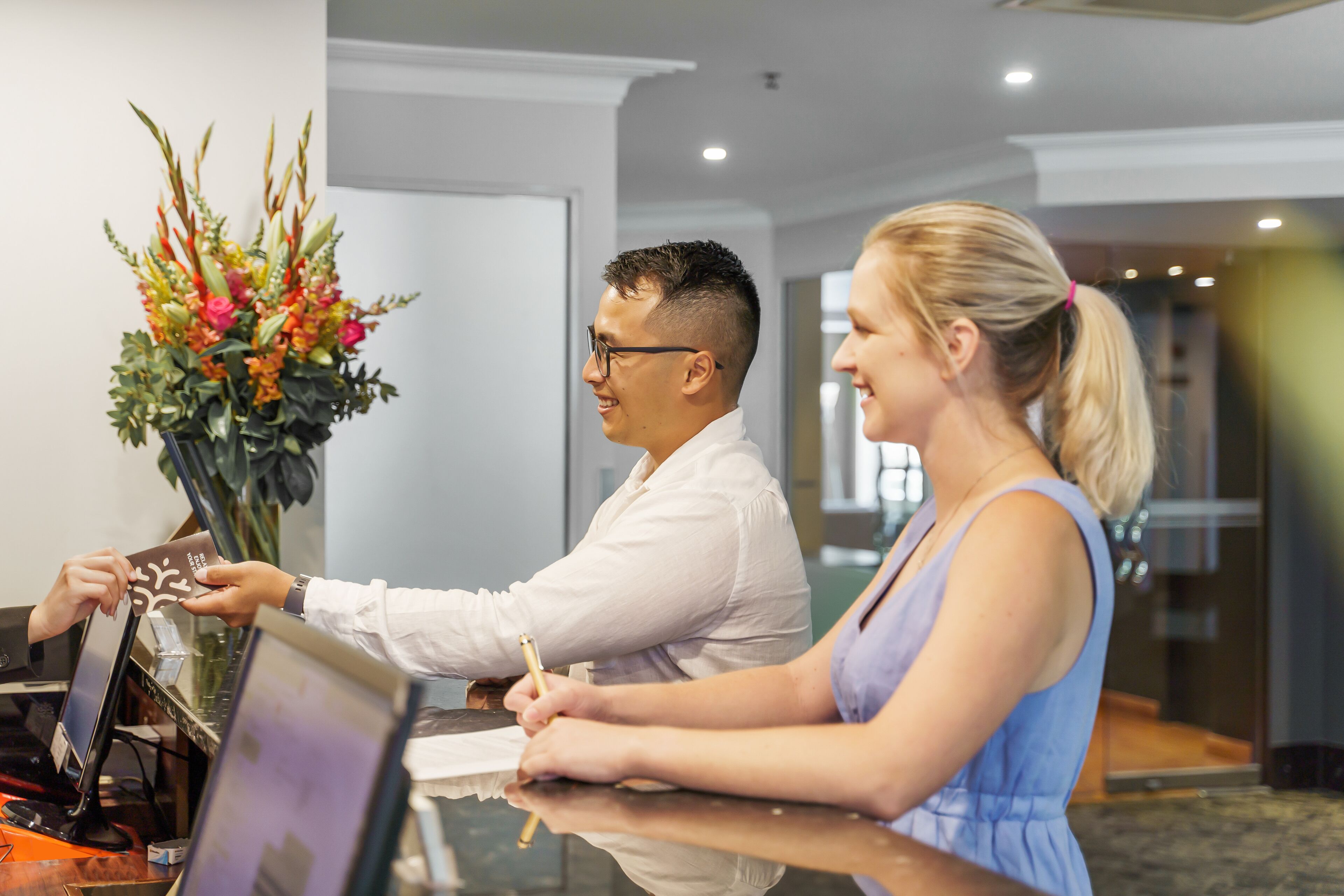 A reception desk with a receptionist and a guest.
