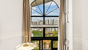 A room with a large arched window, a hanging lamp, and a view of a cityscape. - Parkside Hotel & Apartments Auckland (Auckland)