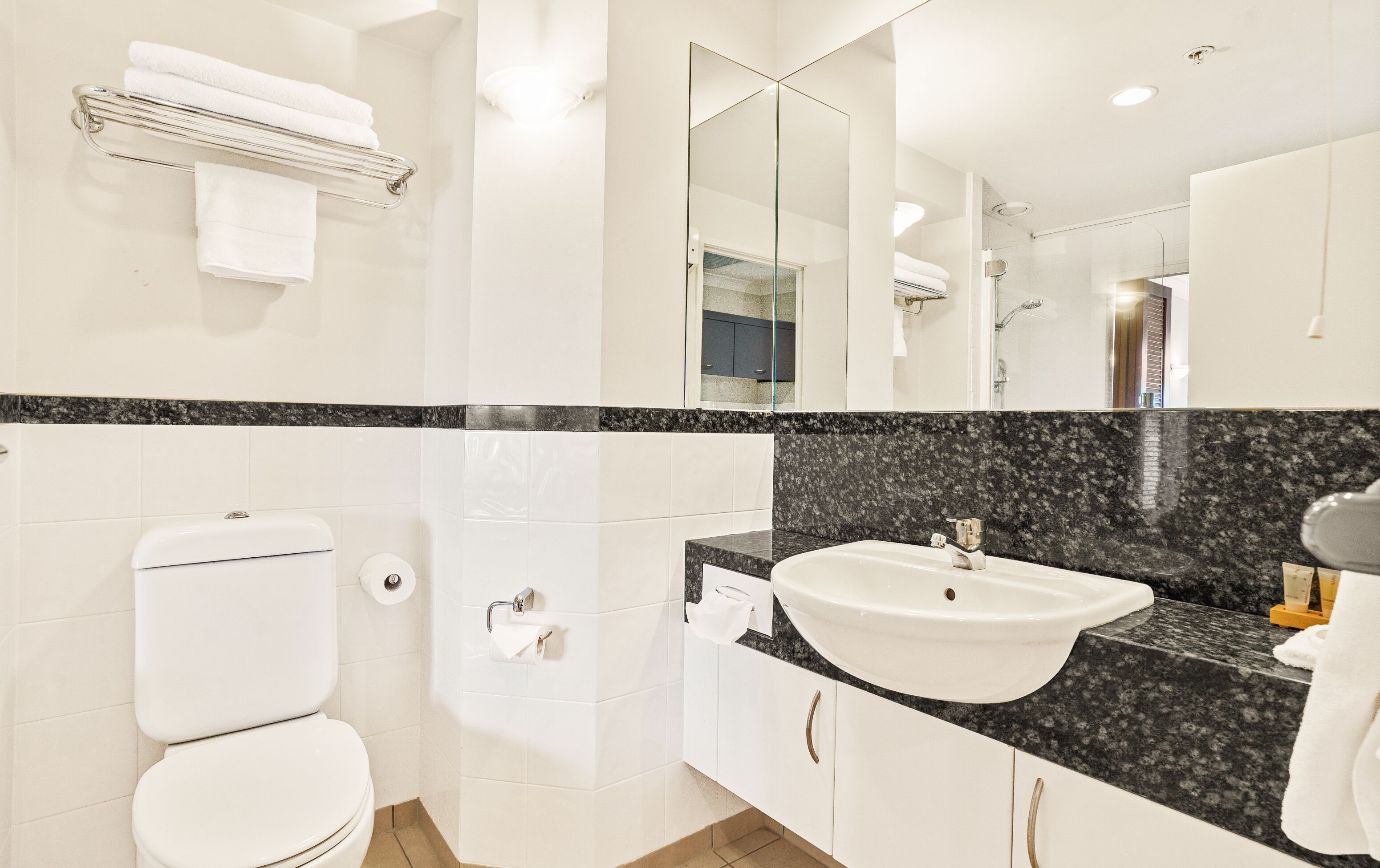 Un baño moderno con inodoro, lavamanos y espejo.