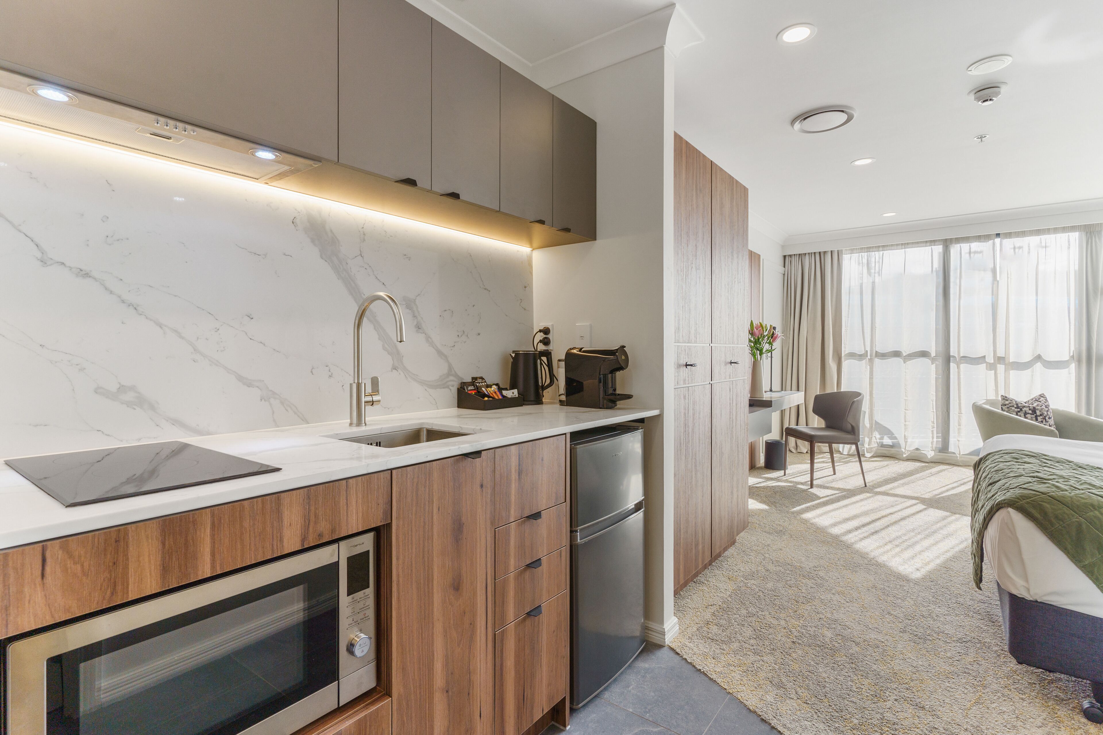 A modern kitchen with a marble countertop, built-in oven, and a dishwasher.