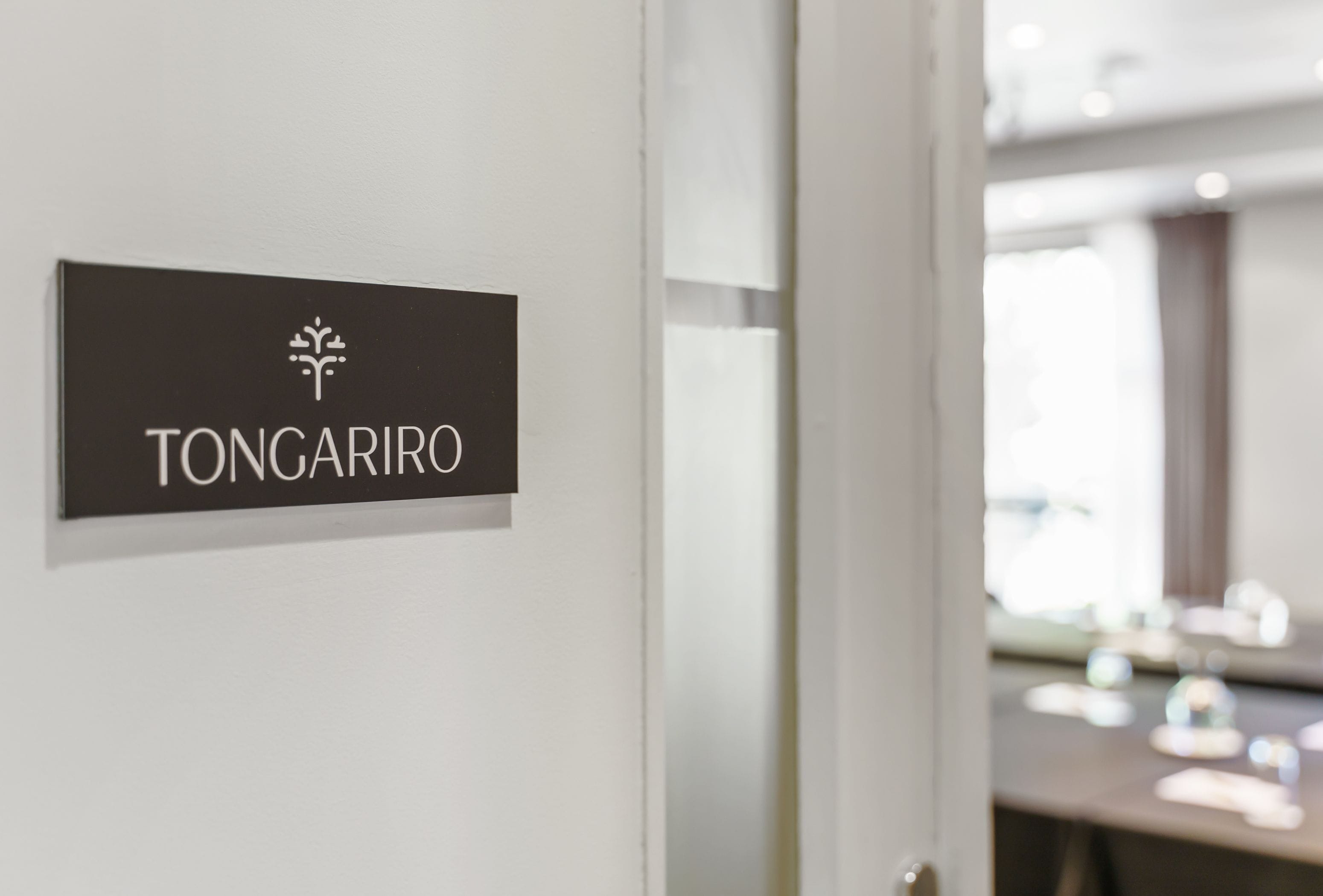 A sign with the name "TONGARIRO" on a white wall.