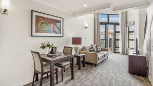 Una sala de estar moderna con comedor, ventanas amplias que ofrecen vistas a la ciudad y una escalera que conduce a un piso superior.