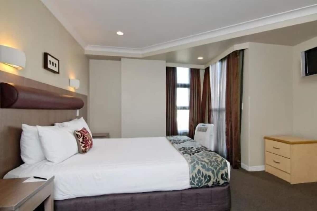 Relax in a spacious room with a large bed, nightstand, and dresser, featuring a flat-screen TV and comfortable bedding.