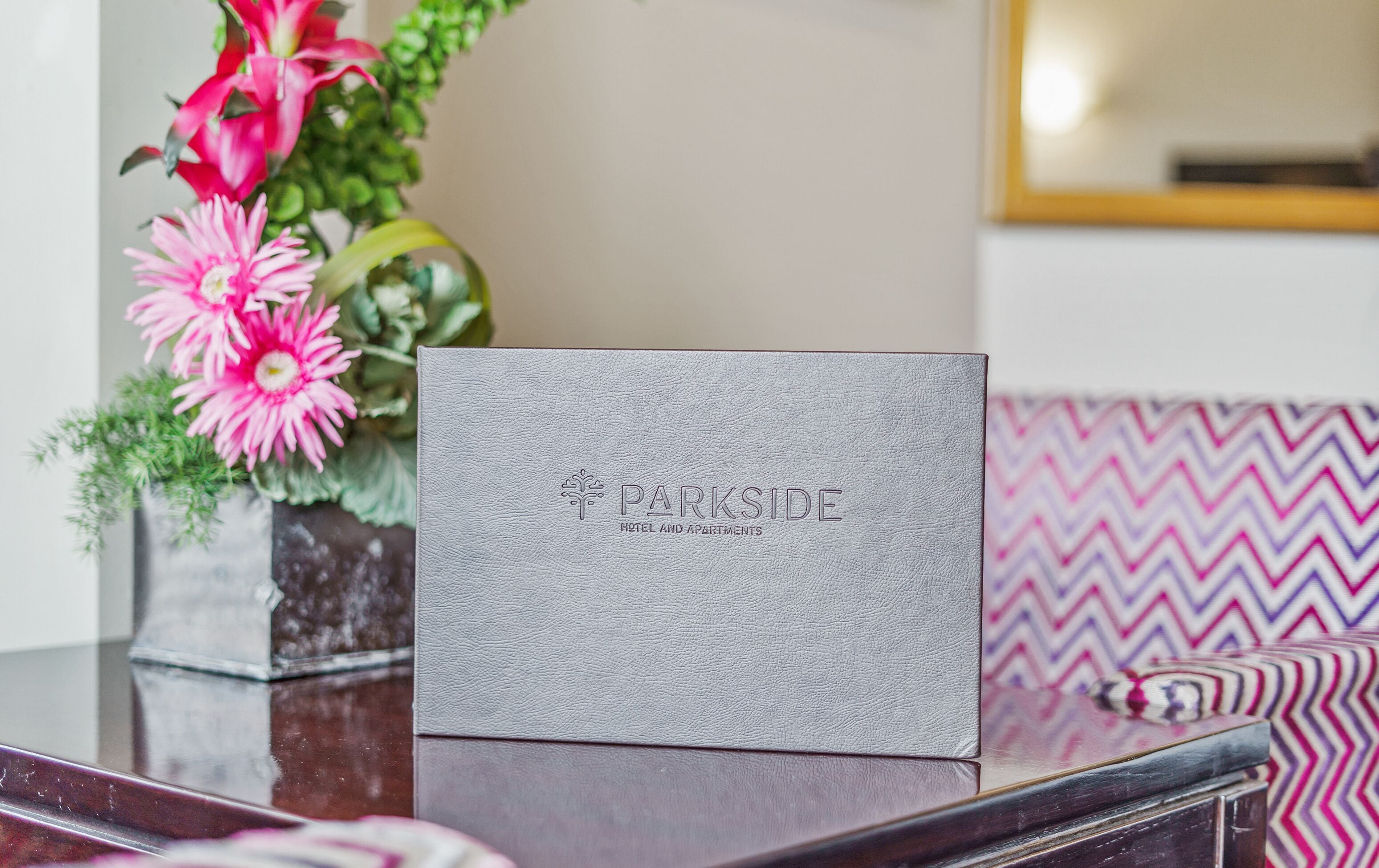 A grey leather-bound book with embossed text 'PARKSIDE HOTEL AND APARTMENTS' on a reflective surface.