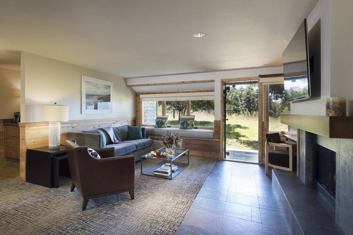 Una sala de estar moderna con sofá, mesa de centro y un comedor con televisor.