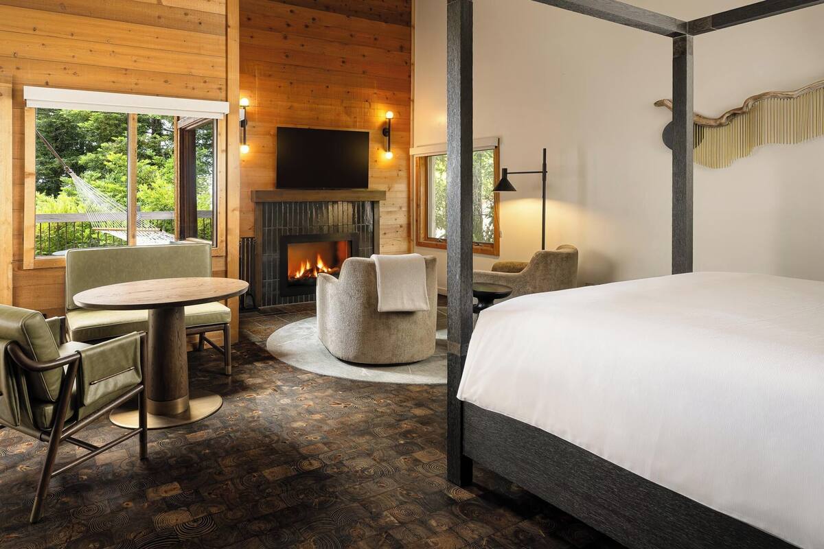 Una habitación acogedora con chimenea, una cama, una mesa redonda y un sofá.