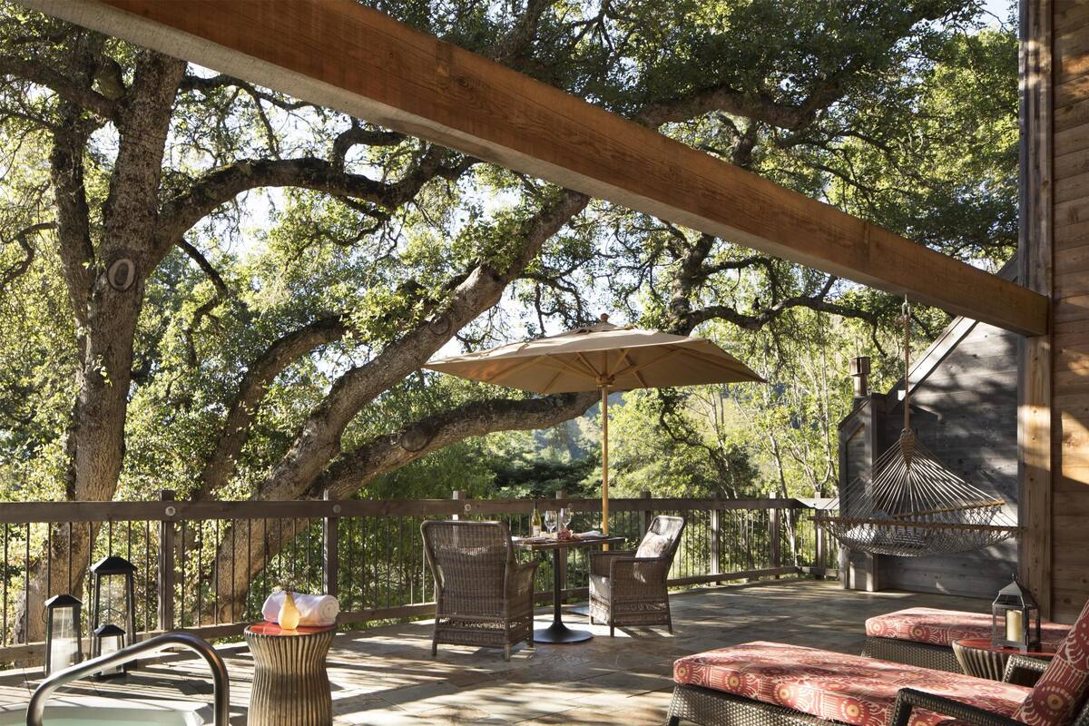Un espacio al aire libre techado con un jacuzzi, mobiliario de mimbre y una pérgola.