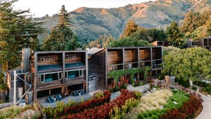Un edificio de madera de varios pisos con zonas de estar al aire libre y un jardín ajardinado.