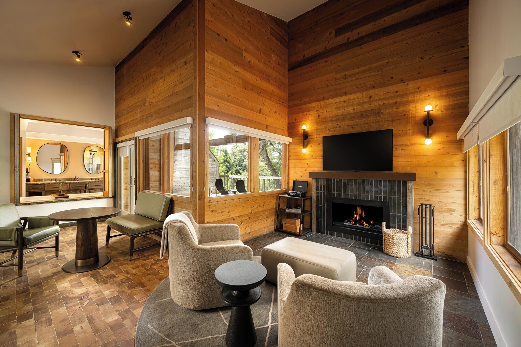 A modern interior with wooden walls, a fireplace, and a dining area with a round table and chairs.