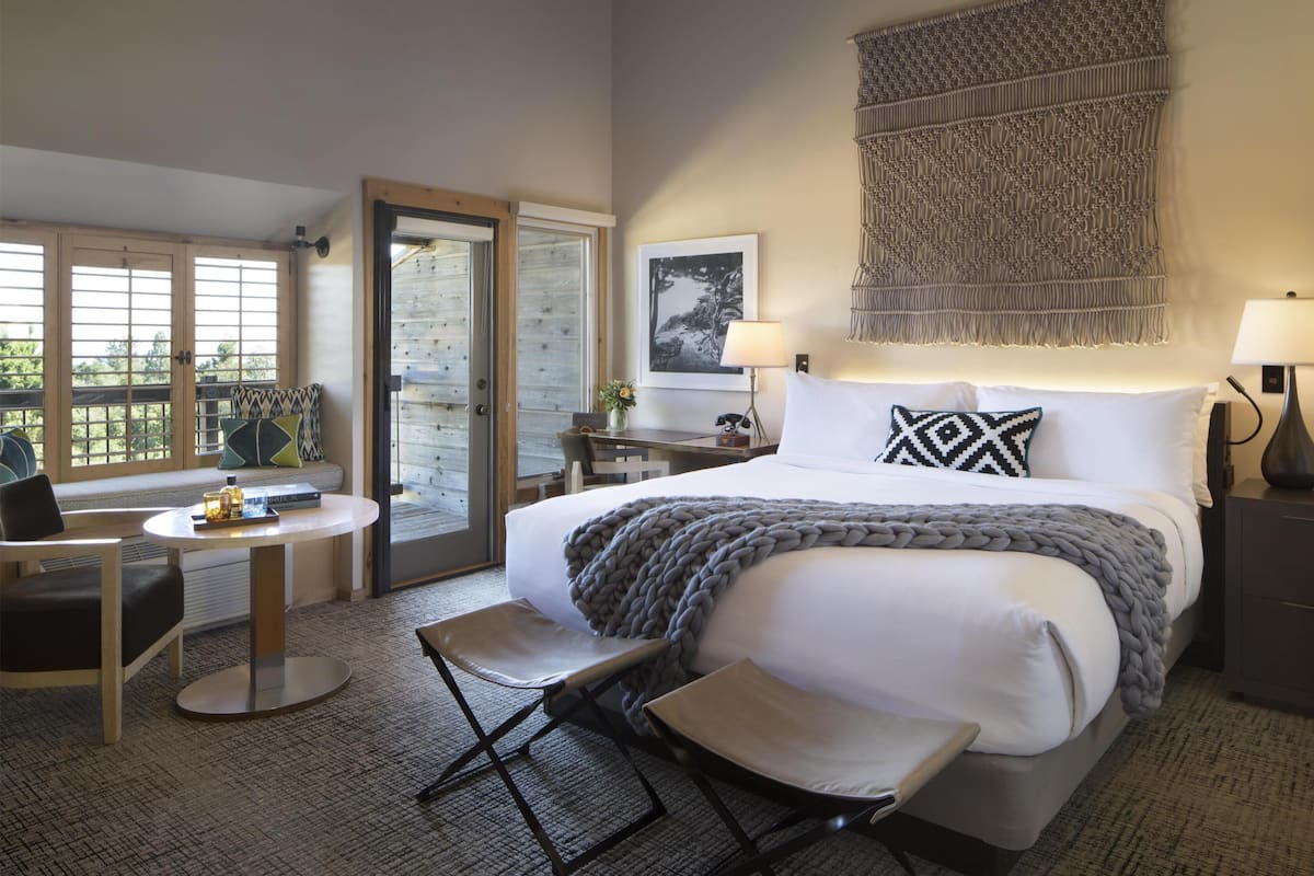 Habitación de hotel con cama, escritorio, silla, ventana y puerta.