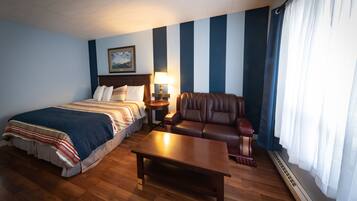 Une chambre d’hôtel comprenant un lit, un canapé, une table basse, une table de chevet, une lampe et une fenêtre avec des rideaux.