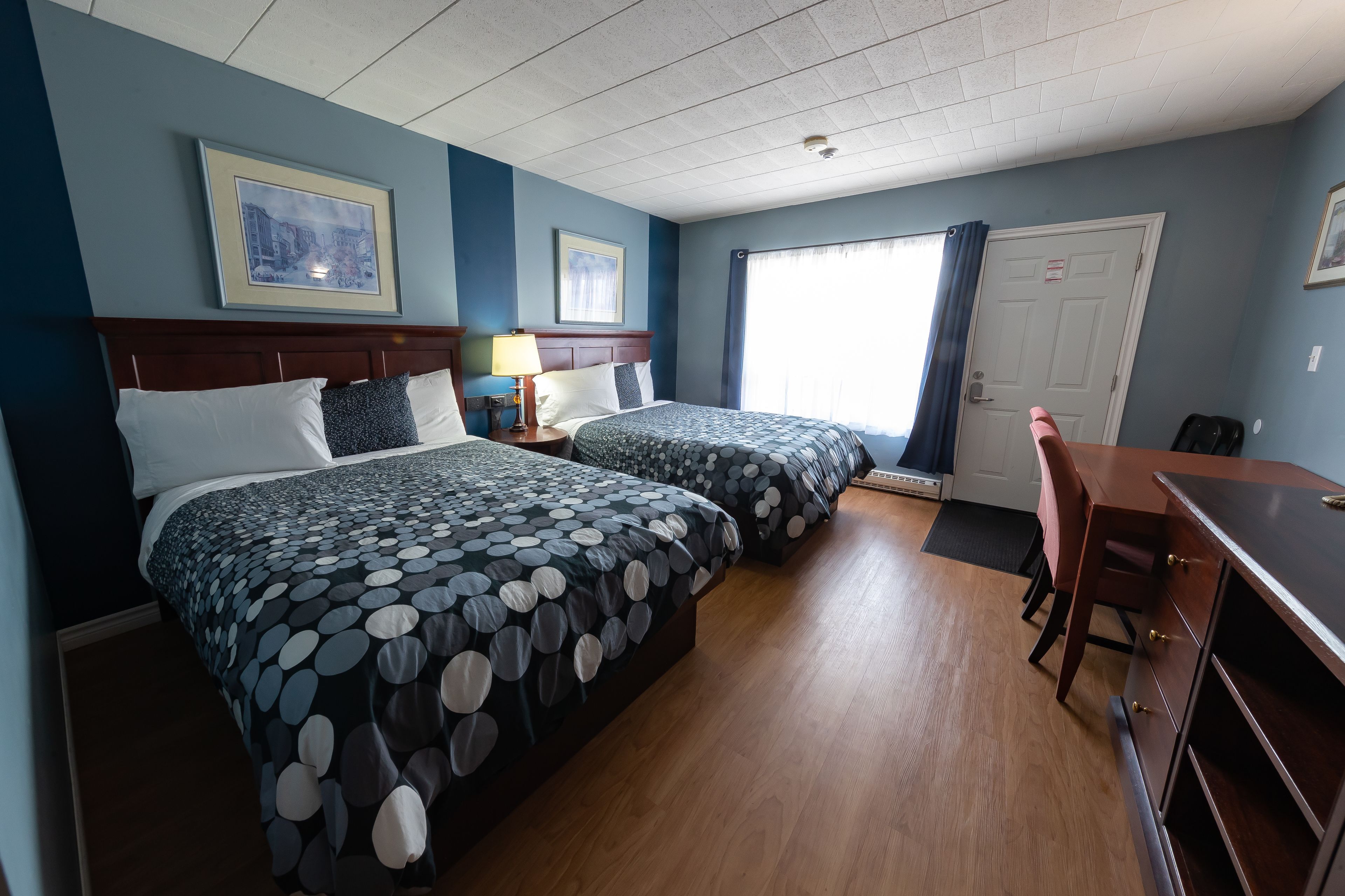 A hotel room with two beds, a desk, and a chair.