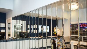 A reception area with a glass partition, a reception desk, a chandelier, and a neon sign. - Villager Lodge (Niagara Falls)