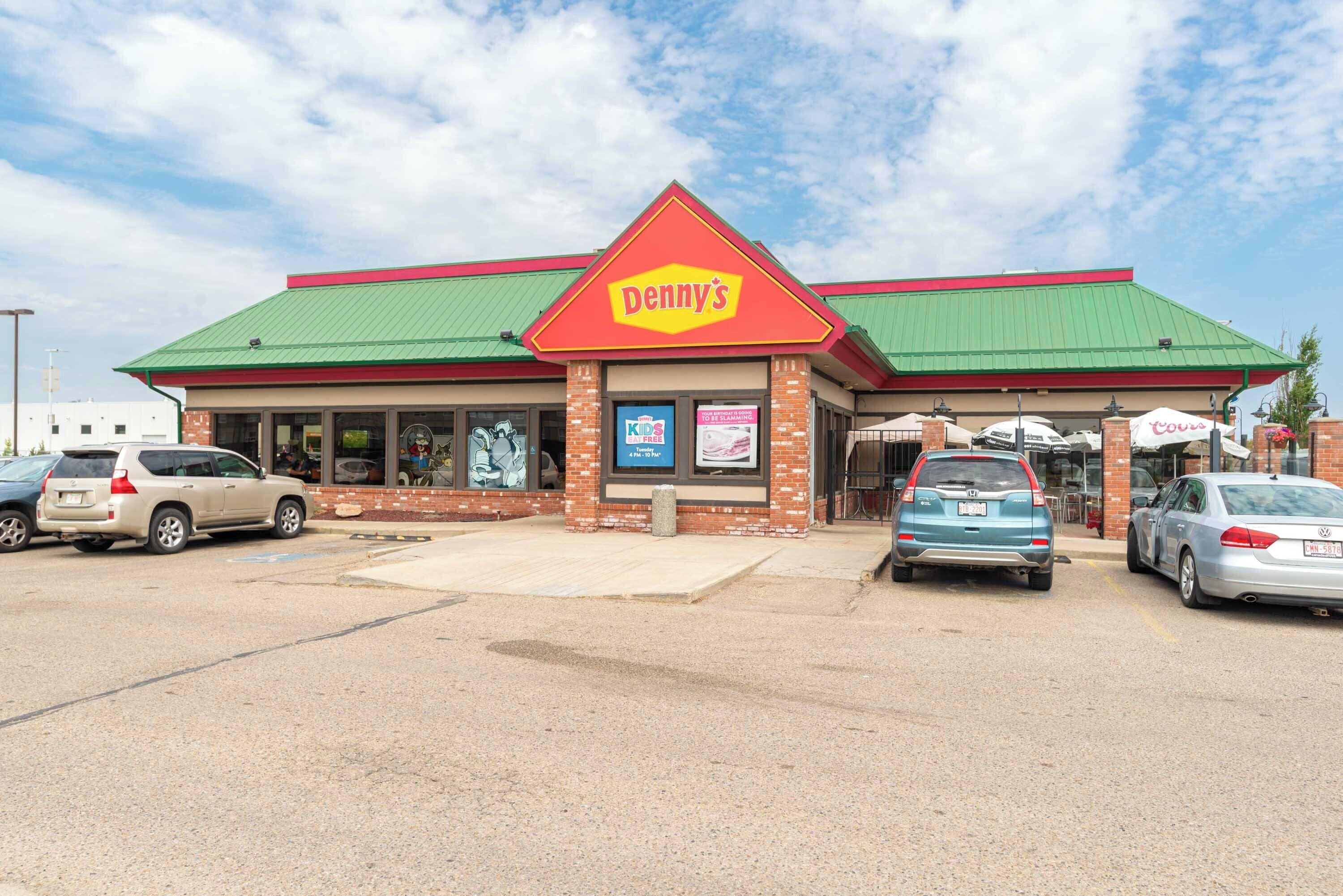 A Denny's restaurant with a green roof and brick facade.