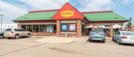 A Denny's restaurant with a green roof and brick facade.