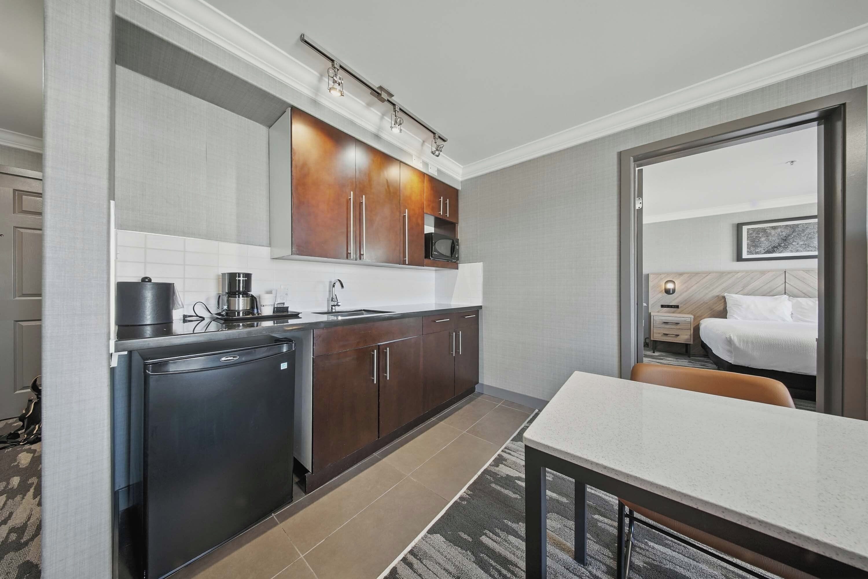 Una habitación de hotel compacta con kitchenette, cama y una pequeña zona de estar.