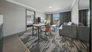 A hotel room with a bed, a desk, a chair, a sofa, and a view of the city.