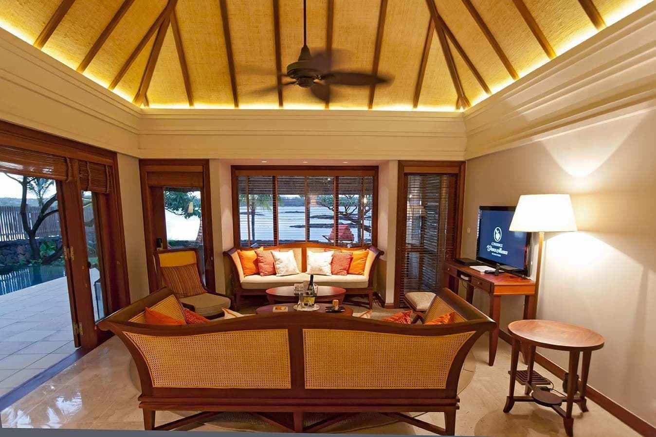 A spacious living area with a ceiling fan, a sofa set, a coffee table, and a television.