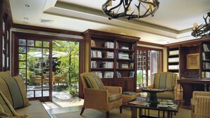 A spacious living room with wicker furniture, a coffee table, and bookshelves.