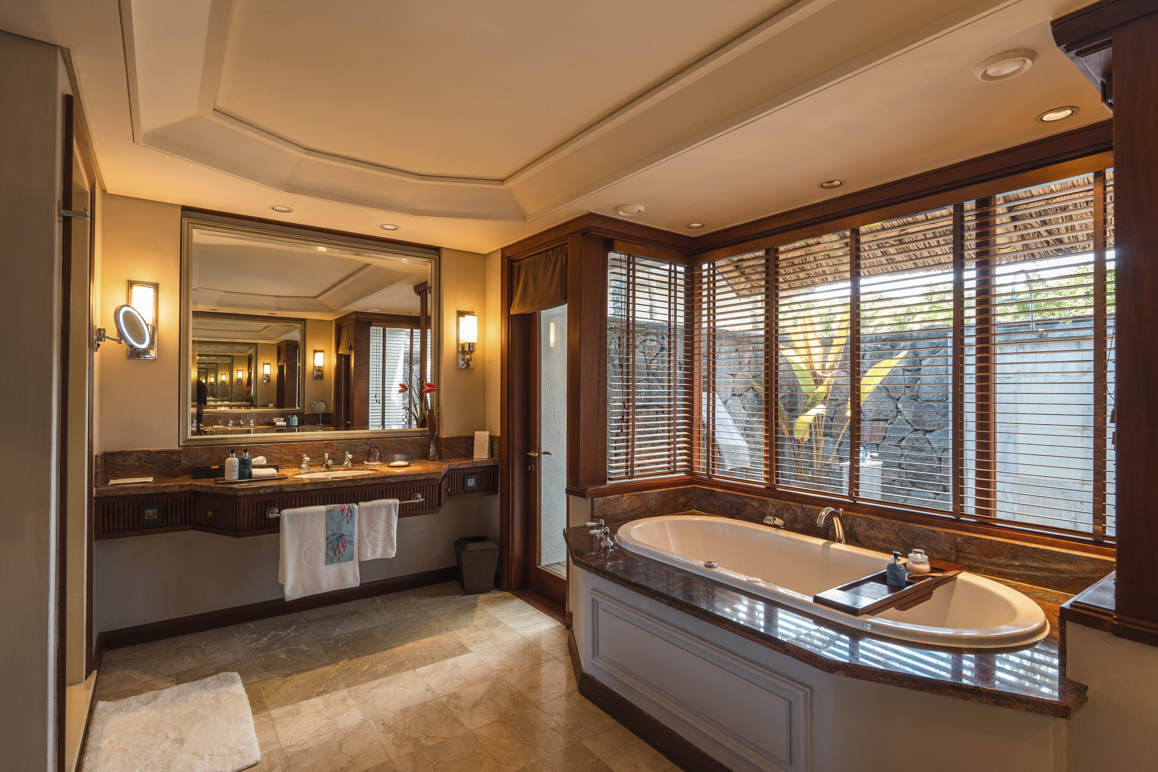 A spacious bathroom with a large bathtub, dual sinks, and a large mirror.
