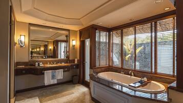 A spacious bathroom with a large bathtub, dual sinks, and a large mirror.