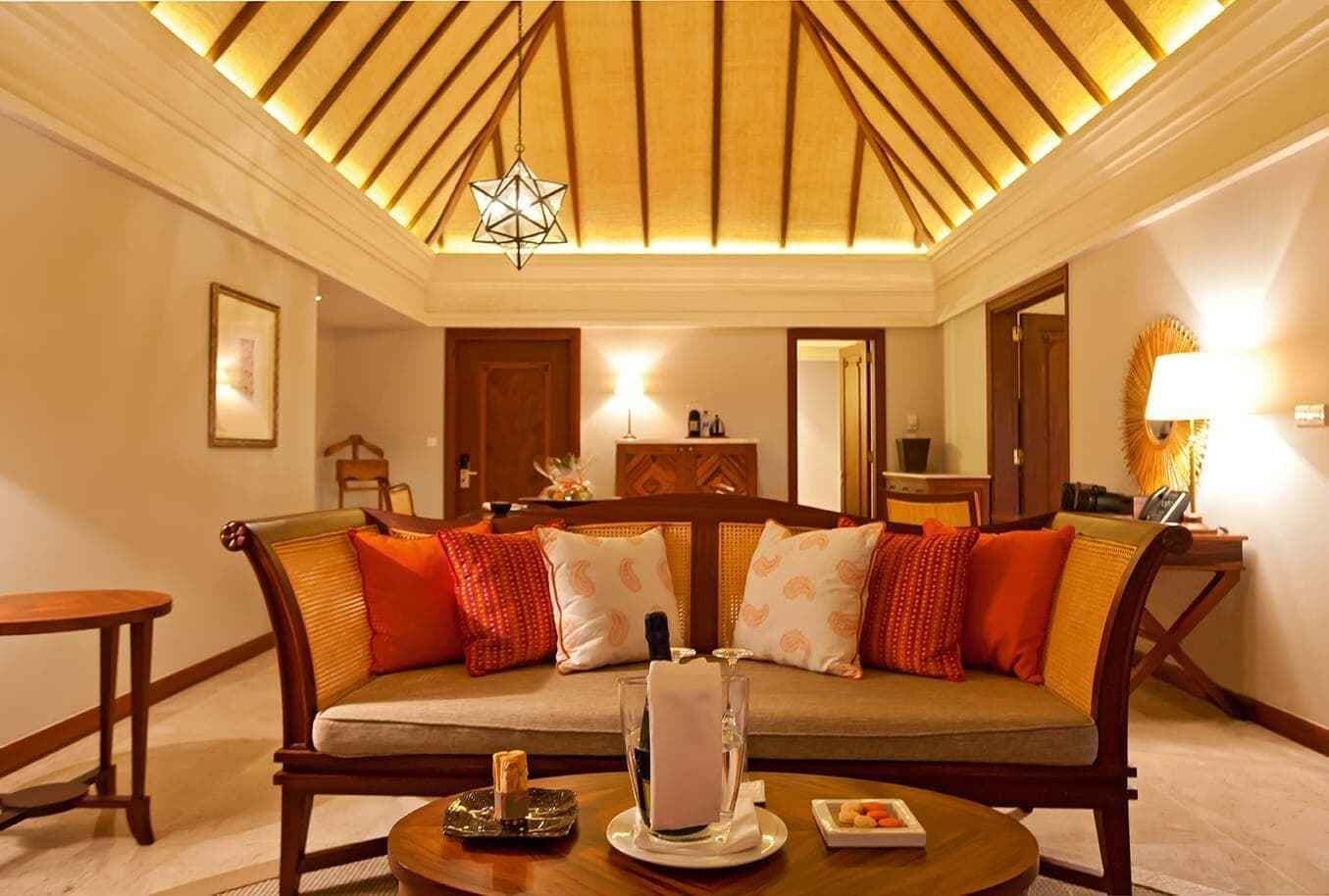 A cozy living room with a wooden sofa, a round coffee table, and a hanging star-shaped light fixture.