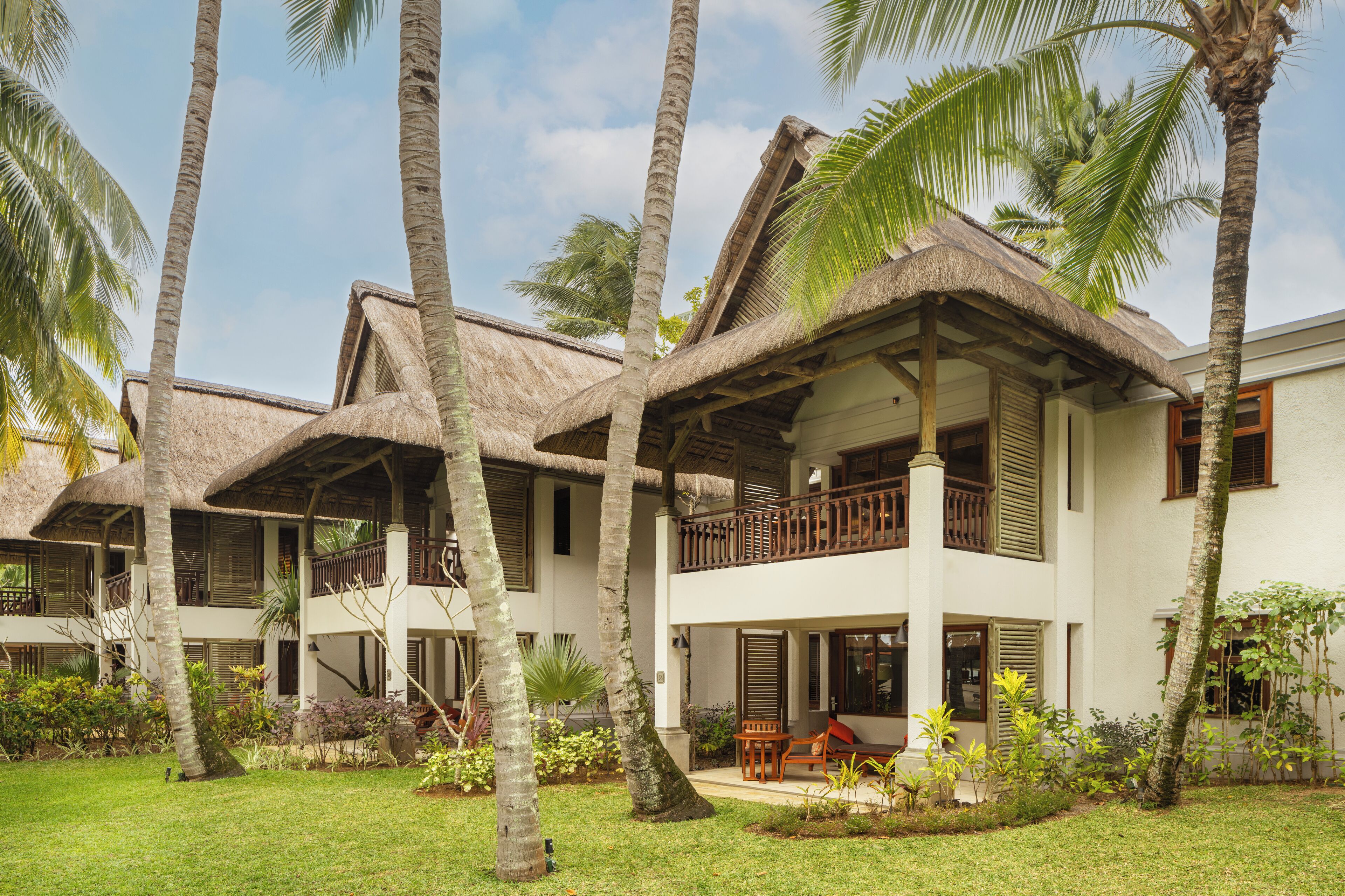 Un complexe hôtelier doté de bungalows aux toits de chaume, d’un espace piscine et d’une végétation tropicale luxuriante.
