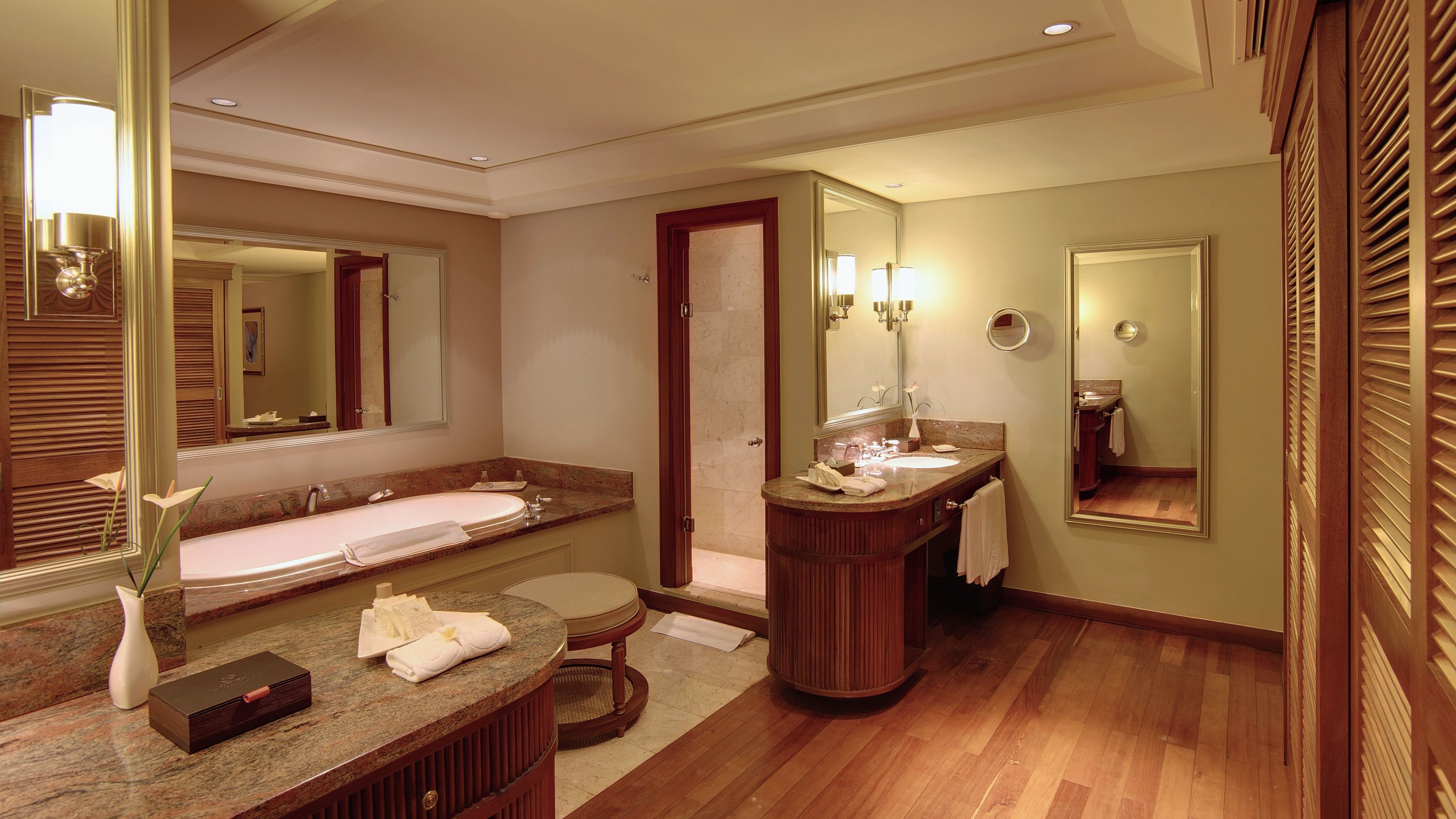 A hotel bathroom with a large sink, vanity, and mirror.