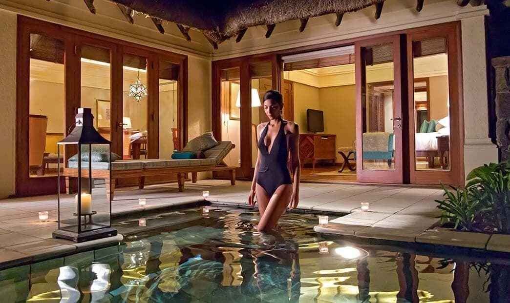 Une femme se tient dans une piscine, avec un espace de détente et un coin repas en arrière-plan.