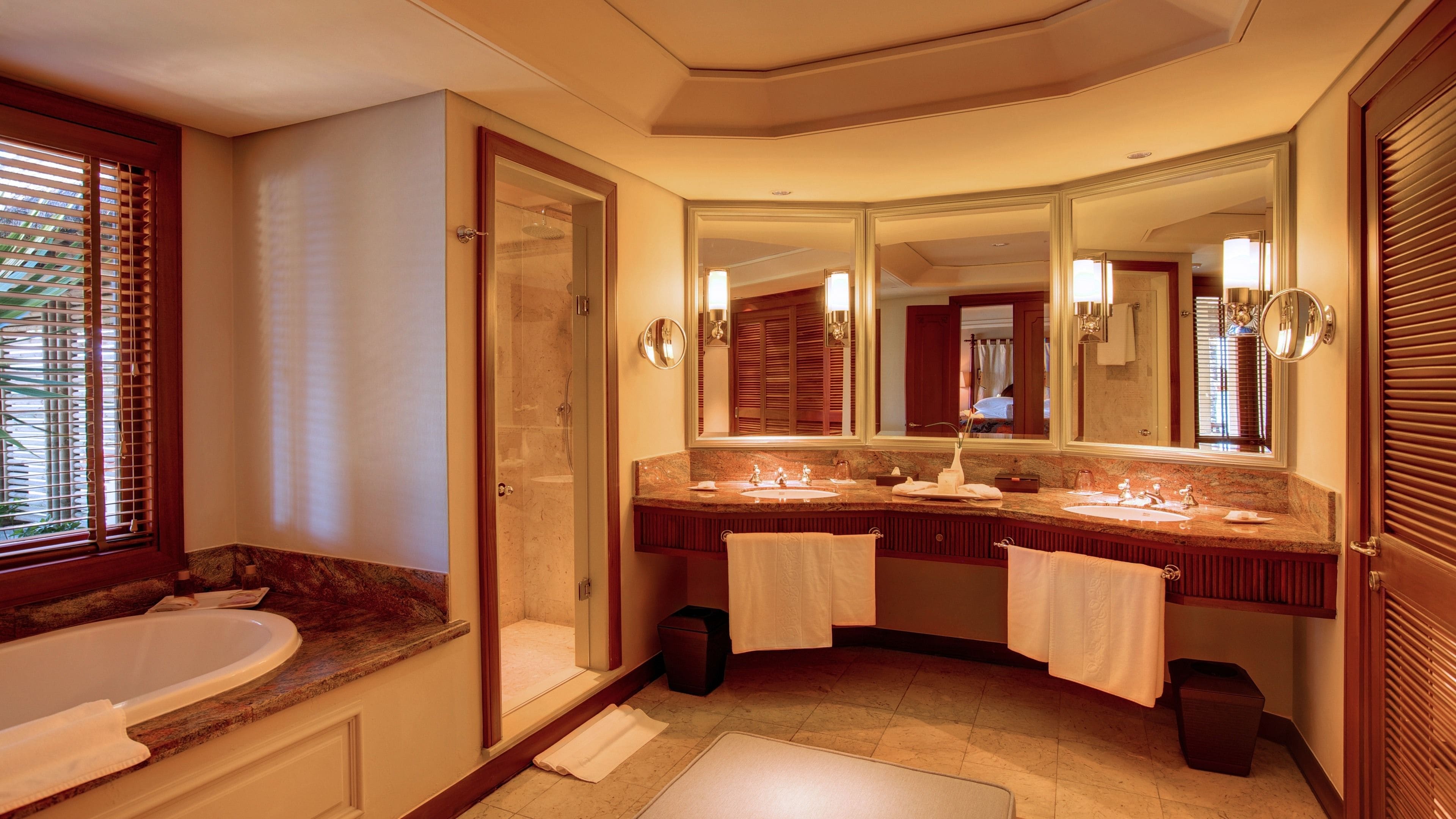 A bathroom with a bathtub, two sinks, a large mirror, and a shower.