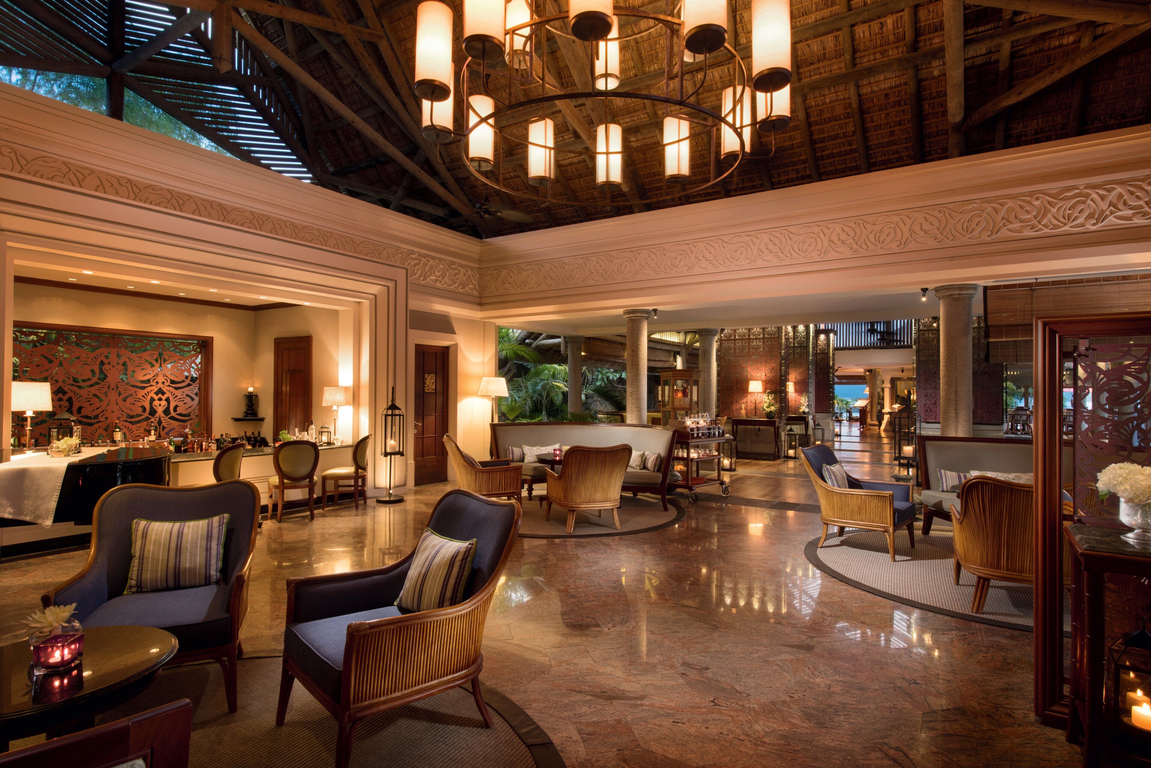 A spacious lobby with a high ceiling, ornate chandeliers, and a variety of seating arrangements including sofas and chairs.